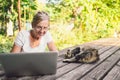 Happy senior old woman with home cat working online with laptop computer outdoor Royalty Free Stock Photo