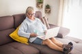 Technology, old age and people concept - happy senior woman in glasses with laptop computer and glass of the at home Royalty Free Stock Photo