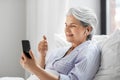senior woman with phone having video call in bed Royalty Free Stock Photo