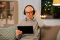 Senior man with tablet pc and headphones at home Royalty Free Stock Photo