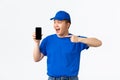 Technology, online shopping and shipping concept. Cheerful smiling asian courier in blue uniform, pointing finger at