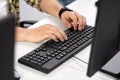 Male hands typing on computer keyboard on table