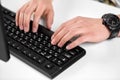 Male hands typing on computer keyboard on table