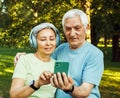 technology, relationship and old people concept - senior couple with smartphone taking selfie and hugging at park Royalty Free Stock Photo