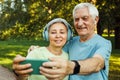 technology, relationship and old people concept - senior couple with smartphone taking selfie and hugging at park Royalty Free Stock Photo