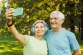 technology, relationship and old people concept - senior couple with smartphone taking selfie and hugging at park Royalty Free Stock Photo