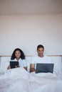 Technology, relax and couple in bed networking on social media or the internet together at home. Happy, smile and young Royalty Free Stock Photo