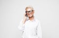 happy old woman with short hair and glasses using smartphone over grey background. Royalty Free Stock Photo