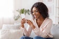 Happy black girl messaging on smartphone and listening music at home Royalty Free Stock Photo