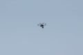 An unmanned aerial vehicle - a quad copter with a camera and a video broadcast flies across the blue sky