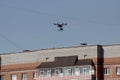 An unmanned aerial vehicle - a quad copter with a camera and a video broadcast flies over the roof of a residential building