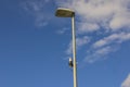 Technology view of light sensor on street lighting pole on blue sky with rare white clouds background. Royalty Free Stock Photo