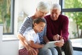 Techology bringing young and old together. a senior couple and their grandson using a digital tablet at home.