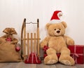 Teddy bear as a santa with an old wooden sleigh and red christmas presents.