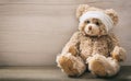 Teddy bear with bandage on a wooden floor