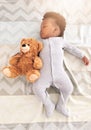 Teddy bear, bed and baby sleeping in home with lens flare for rest, nap time and dreaming in nursery. Childcare, newborn Royalty Free Stock Photo