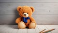 A teddy bear with a blue bow is sitting on a wooden floor. The scene is simple and peaceful, with the teddy bear being the main Royalty Free Stock Photo