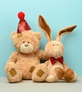 Teddy bear in a cap and a cute teddy hare with long ears, a red butterfly is tied around the neck