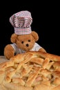 Teddy bear pastry chef with apple pie Black background Royalty Free Stock Photo