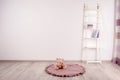 Teddy bear on floor and shelving unit near wall in child room