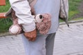 A teddy bear in the hand of a man. old person walk on the street. Grandpa holds a toy of a grandson or granddaughter`s child