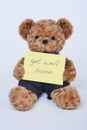 Teddy bear holding a yellow sign saying Get Well Soon isolated on white background