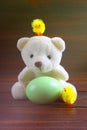 Teddy Bear holding an Easter egg, chicken, wood background Royalty Free Stock Photo