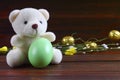 Teddy Bear holding an Easter egg, chicken, wood background Royalty Free Stock Photo