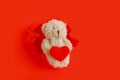 Teddy bear holding Hug red heart in paws. Toy teddy bear climbs out of torn paper holes with love heart symbol for