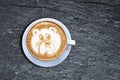 Teddy bear latte art coffee cup on textured black shist with oblique light Royalty Free Stock Photo