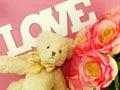 Teddy bear with love word and artificial roses flower