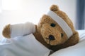 Teddy bear lying sick in bed With a headband and a cloth covered Royalty Free Stock Photo