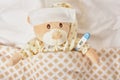 Teddy bear lying sick in bed with with thermometer Royalty Free Stock Photo