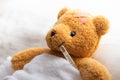 Teddy bear lying sick in hospital bed with with thermometer Royalty Free Stock Photo