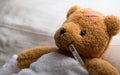 Teddy bear lying sick in hospital bed with with thermometer and plaster. Healthcare and medical concept Royalty Free Stock Photo