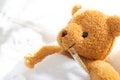 Teddy bear lying sick in hospital bed with with thermometer Royalty Free Stock Photo