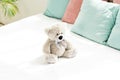 Teddy bear near pink and blue pillows on white bedding in bedroom Royalty Free Stock Photo