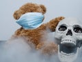 Teddy bear and open-mouthed skull with covid 19 coronavirus mask surrounded by smoke