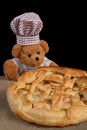 Teddy bear pastry chef with apple pie Black background Royalty Free Stock Photo