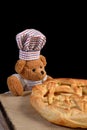 Teddy bear pastry chef with apple pie Black background Royalty Free Stock Photo