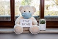 Teddy bear with protective medical mask in quarantine near the window. Stay home concept Royalty Free Stock Photo