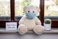 Teddy bear with protective medical mask in quarantine near the window. Stay home concept Royalty Free Stock Photo