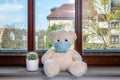 Teddy bear with protective medical mask in quarantine near the window. Stay home concept Royalty Free Stock Photo