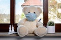 Teddy bear with protective medical mask in quarantine near the window. Stay home concept Royalty Free Stock Photo