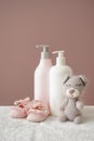 Teddy bear with shoes and cosmetics for baby on soft towel against color background