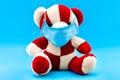 Teddy bear in a sick mask on a blue background.
