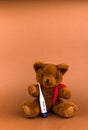 Teddy Bear is sick. Teddy bear toy and thermometer on a brown background with copy space