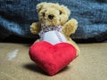 Teddy bear sits with a baseball and with a red heart