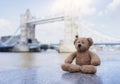 Teddy bear sitting alone with blurry london tower bridge background, The forgotten bear sitting by the river, lost property, Royalty Free Stock Photo