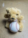 Teddy bear sitting with a baseball ball